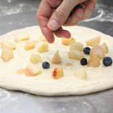 Sweet pizza with crème fraîche lemon curd base, blueberries and white peach and fresh basil